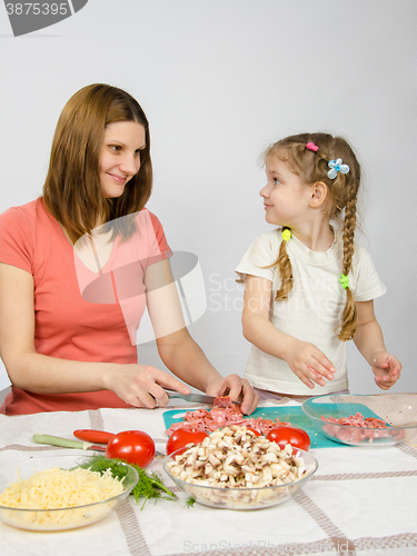 Image of Little six year old girl joyful enthusiasm helps mum to prepare food