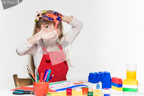 Image of The beautiful little girl with hands in the paint