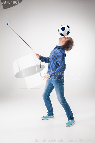 Image of The portrait of man with ball, holding selfie stick on white background