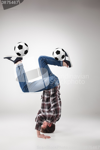 Image of Portrait  of young man, practicing yoga with football balls