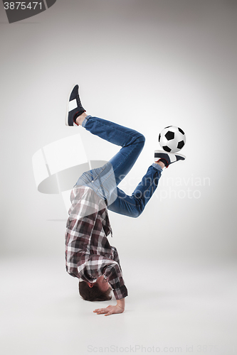 Image of Portrait  of young man, practicing yoga with football ball