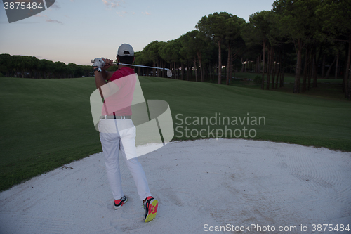 Image of golfer hitting a sand bunker shot on sunset