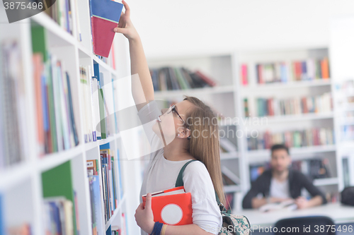 Image of famale student selecting book to read in library