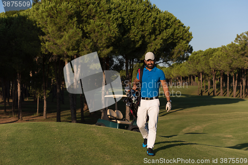 Image of golfer  walking and carrying golf  bag