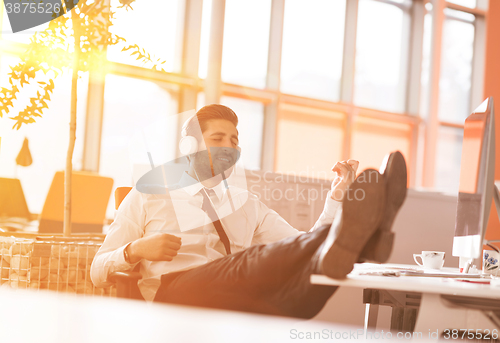 Image of relaxed young businessman first at workplace at early morning