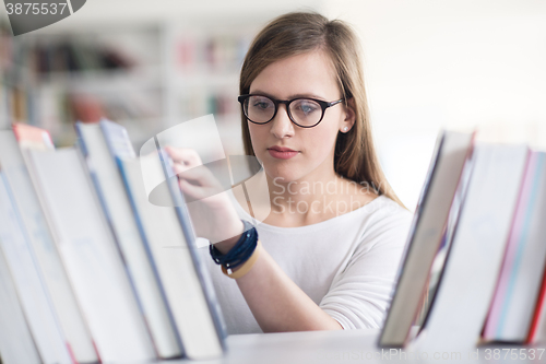 Image of portrait of famale student selecting book to read in library