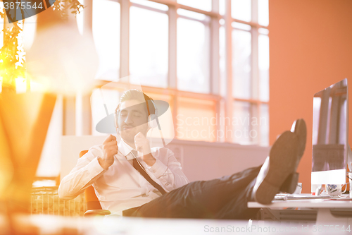 Image of relaxed young businessman first at workplace at early morning