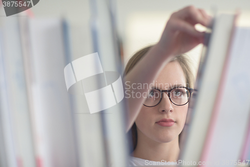 Image of portrait of famale student selecting book to read in library