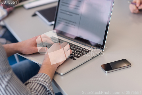 Image of close up of business man hands typing on laptop with team on mee