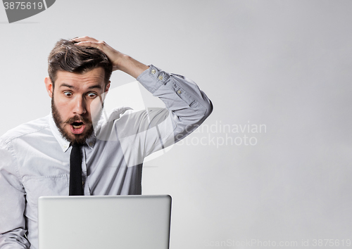 Image of The young surprised man with his laptop computer