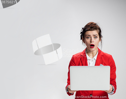 Image of Surprised girl holding laptop over gray background