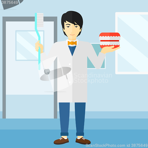 Image of Dentist with dental jaw model and toothbrush.
