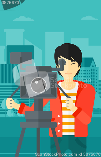 Image of Cameraman with movie camera on a tripod.