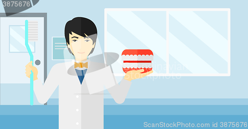 Image of Dentist with dental jaw model and toothbrush.