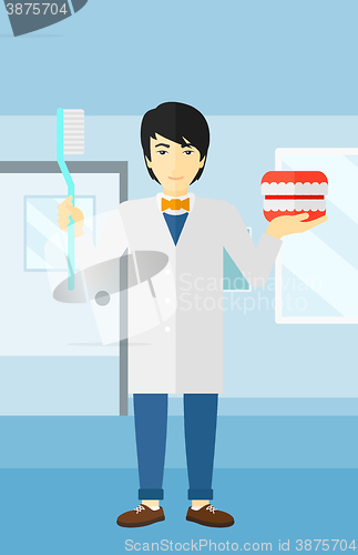 Image of Dentist with dental jaw model and toothbrush.