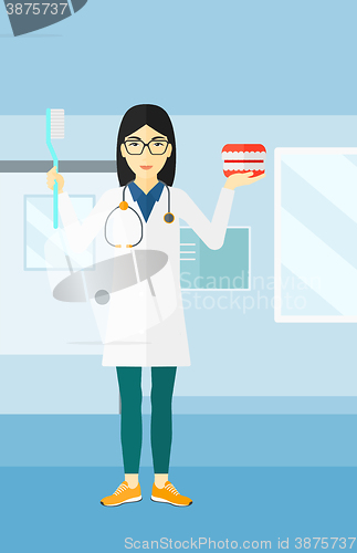 Image of Dentist with dental jaw model and toothbrush.