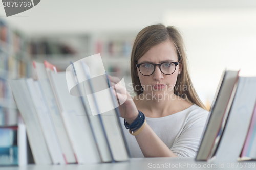 Image of portrait of famale student selecting book to read in library