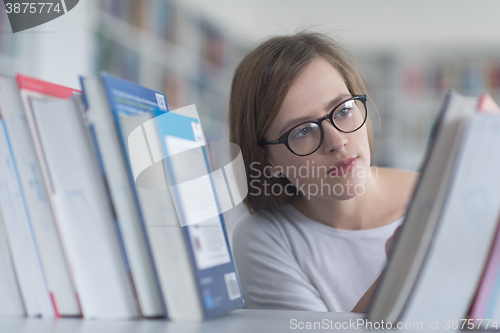 Image of portrait of famale student selecting book to read in library