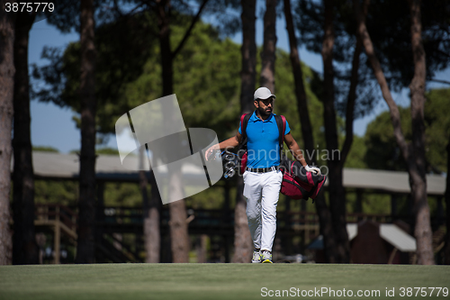 Image of golf player walking and carrying bag