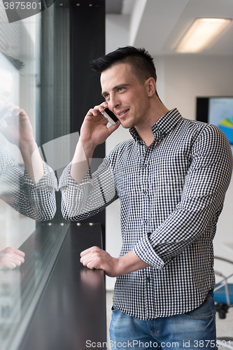 Image of young business man speaking on  smart phone at office