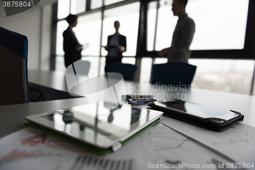 Image of close up of tablet, business people on meeting in background