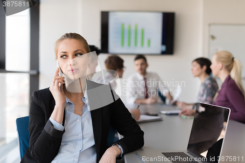 Image of business woman speeking on phone at office with team on meeting 