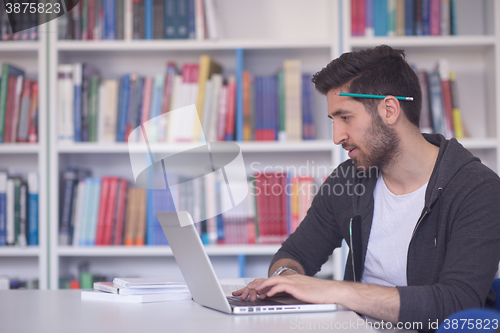 Image of student in school library using laptop for research