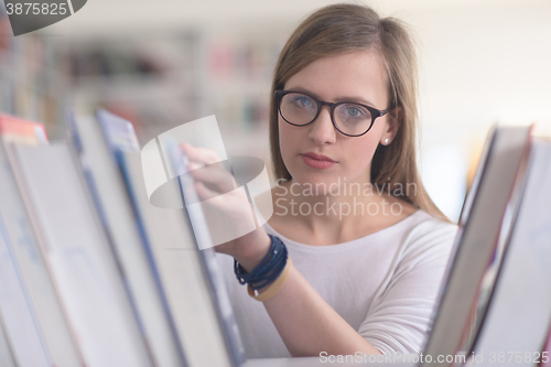 Image of portrait of famale student selecting book to read in library