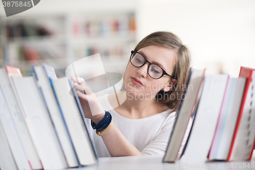 Image of portrait of famale student selecting book to read in library