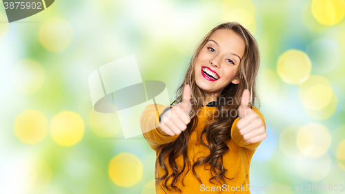 Image of happy young woman or teen girl showing thumbs up