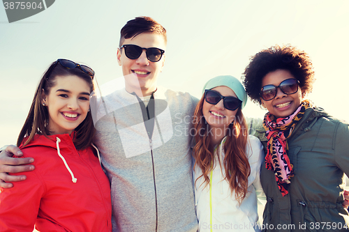 Image of happy teenage friends in shades hugging outdoors