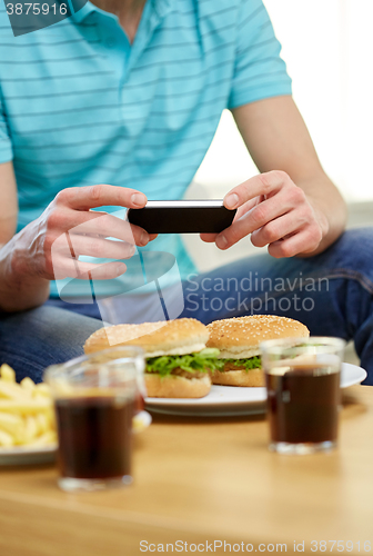 Image of close up of man with smartphone picturing food
