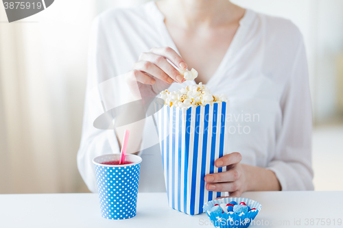 Image of woman eating popcorn with drink and candies