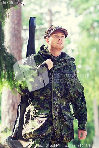 Image of young soldier or hunter with gun in forest