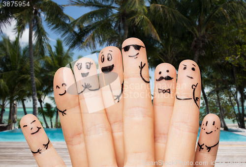 Image of close up of fingers with smiley faces on beach