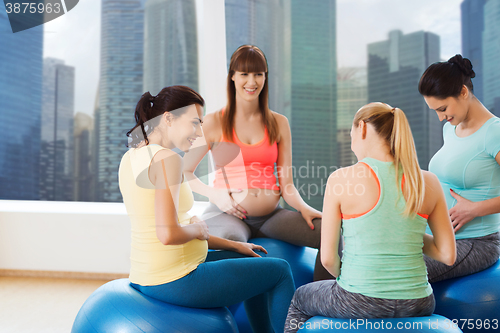 Image of happy pregnant women sitting on balls in gym