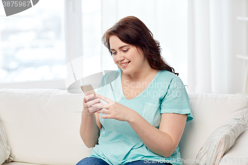 Image of happy plus size woman with smartphone at home