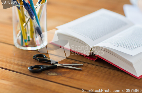 Image of close up of pens, book and scissors on table