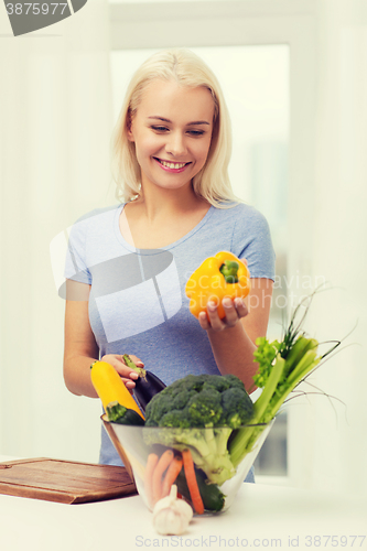 Image of smiling young woman cooking vegetables at home