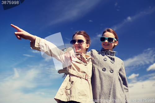 Image of happy little girls hugging and pointing finger