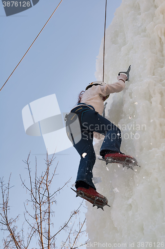 Image of Girl climbs upward on ice climbing competition