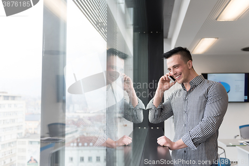 Image of young business man speaking on  smart phone at office