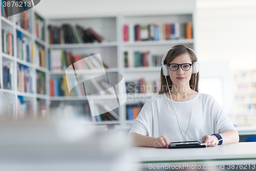 Image of female student study in library, using tablet and searching for 