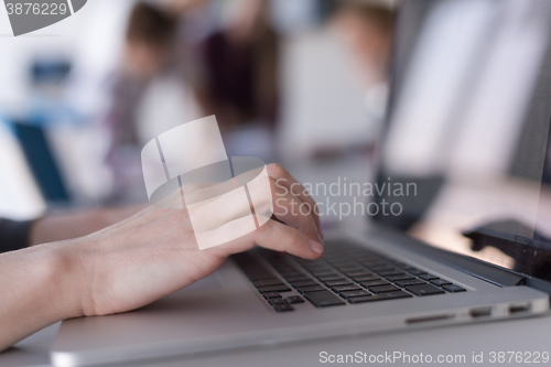 Image of close up of business womans hand typing on laptop with team on m