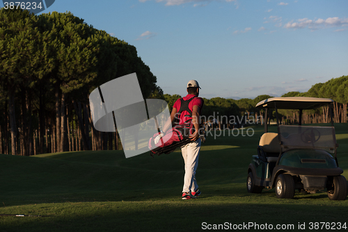 Image of golfer  walking and carrying golf  bag