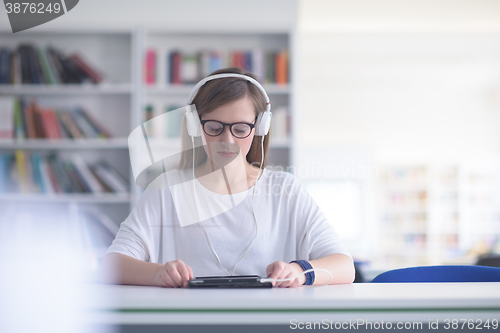 Image of female student study in library, using tablet and searching for 