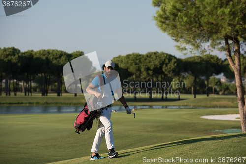 Image of golfer  walking and carrying bag