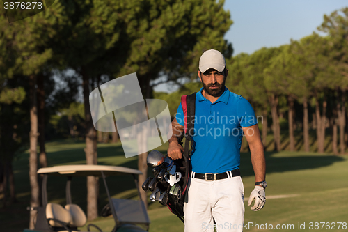 Image of golfer  walking and carrying golf  bag