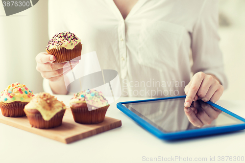 Image of close up of woman with cupcakes and tablet pc