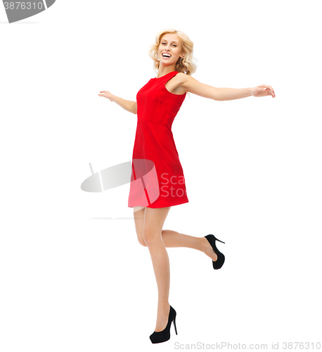 Image of happy young woman in red dress jumping high